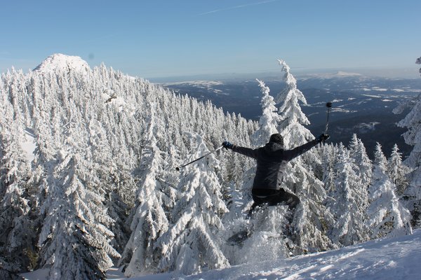 Verschneite Landschaft, ein Mann springt mit den Schneeschuhen in die Luft