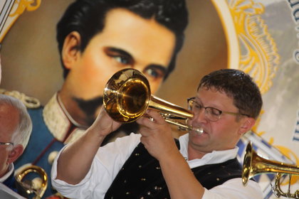 Musiker beim Oktoberfest. Im Hintergrund Bild von König Ludwig