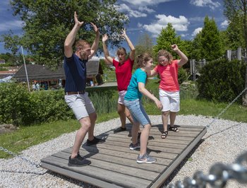 Familie auf einem Gerät im Motorikpfad