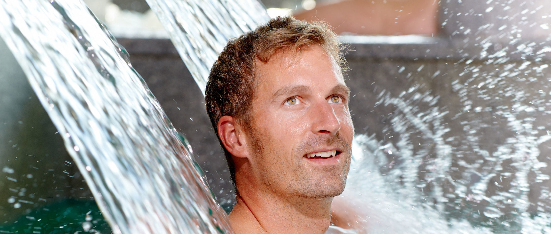 Mann unter der Wasserfallnackenmassage in der AQACUR Badewelt 
