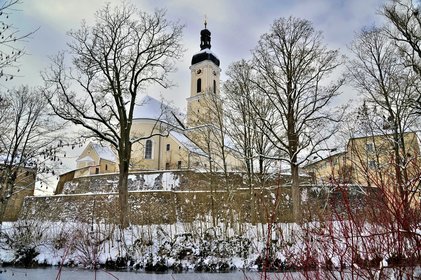 Blick durch die verschneiten Bäume hindurch zur Kötztinger Kirche