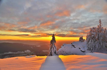 Blick über den verschneiten Bergrand hinein ins Abendrot