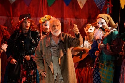 Im Vordergrund der Schauspieler des Mühlhiasl mit weißem Bart und im Hintergrund die Begleitpersonen mit Gesichtsmasken 