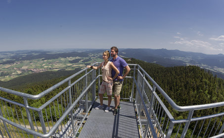 Paar steht auf der Aussichtsplattform im Hintergrund sieht man den Ausblick über die Landschaft