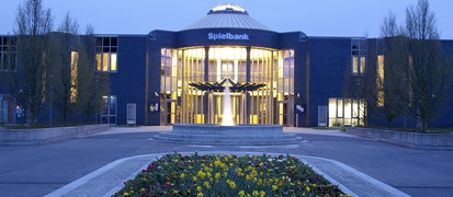 Hausansicht der Spielbank Bad Kötzting mit Brunnen und Blumen im Vordergrund 