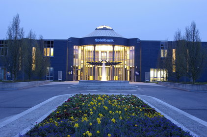 Hausansicht der Spielbank Bad Kötzting mit Brunnen und Blumen im Vordergrund 