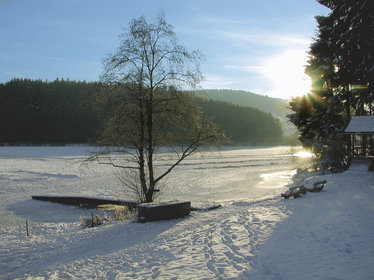 zugefrorener See in einer Winterlandschaft, die Sonne scheint