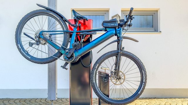 Ein Fahrrad hängt auf dem Rad-Retter und wird repariert. 
