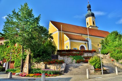 Blick auf die gelbe Kirche, der Treppenaufgang ist mit Blumen geziehrt