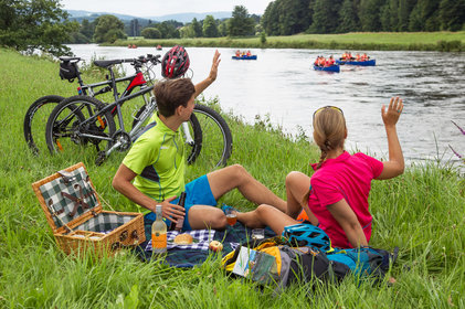 Winkendes Paar beim Picknick am Radweg